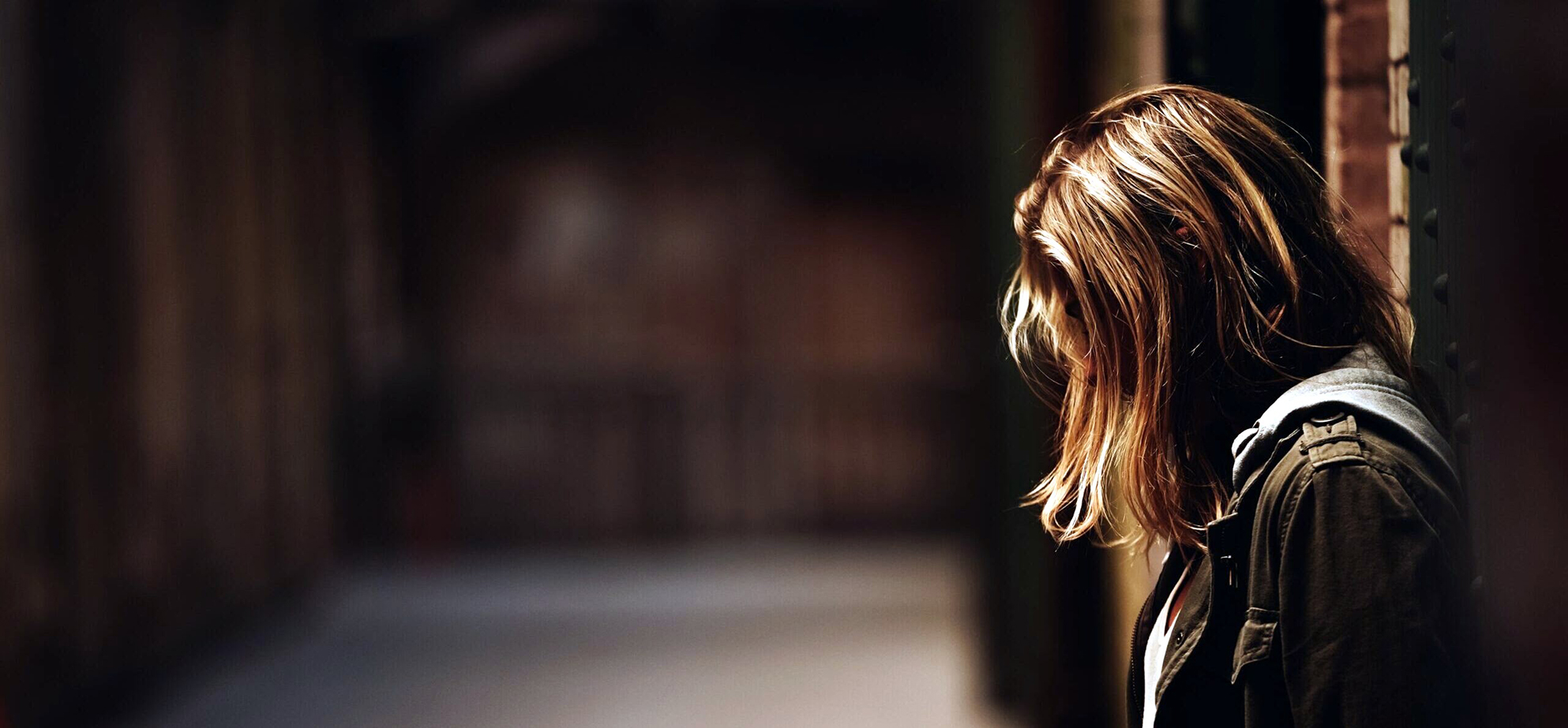 Young woman sitting alone with her head down, representing someone questioning their relationship with marijuana.